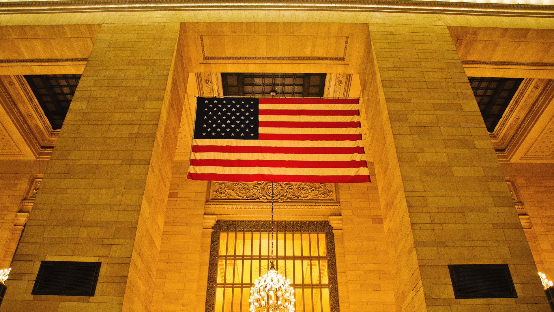 American flag displayed in ornate gold stone building interior with architectural details