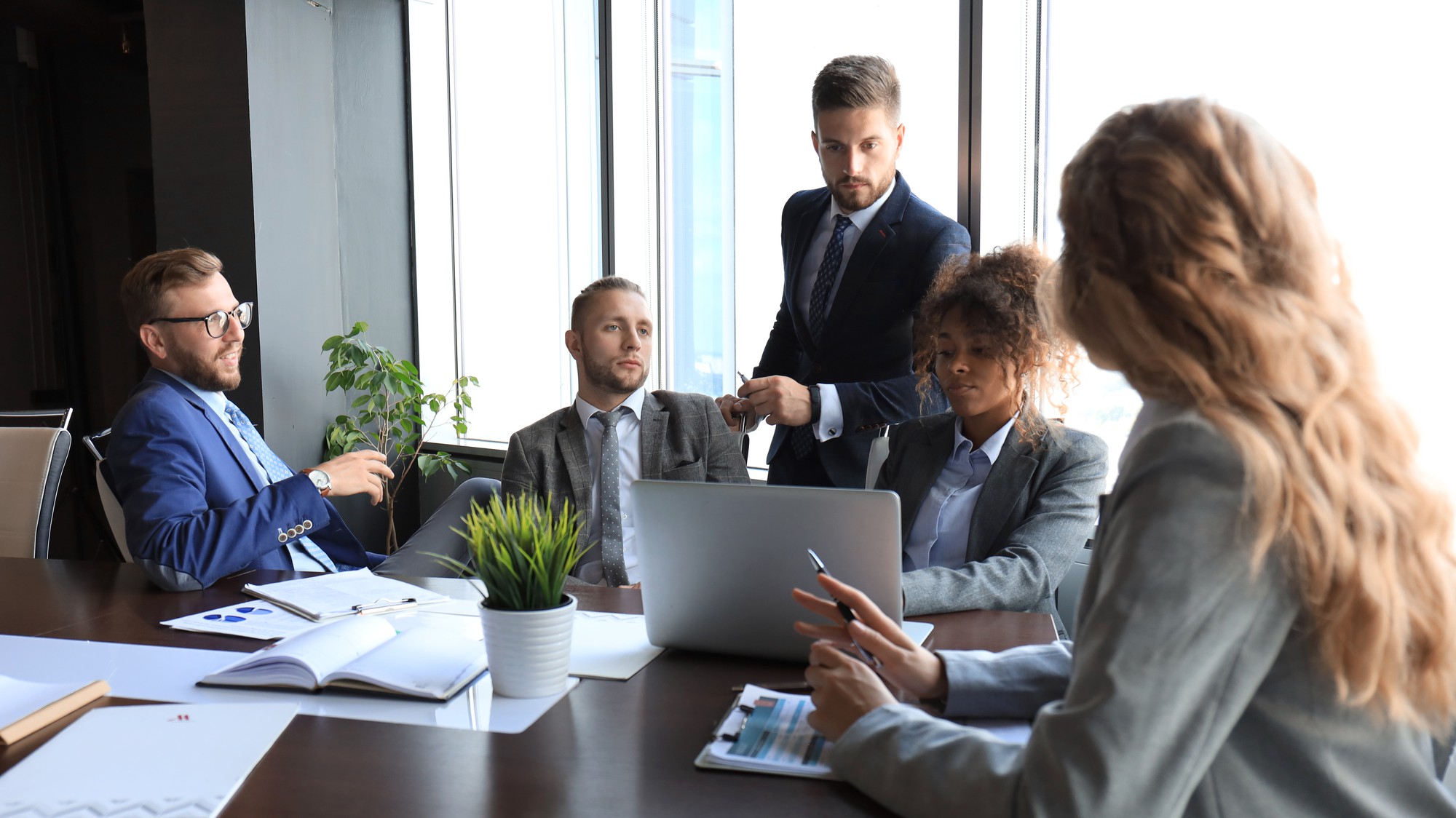 Professional business team meeting around table with laptop in modern office