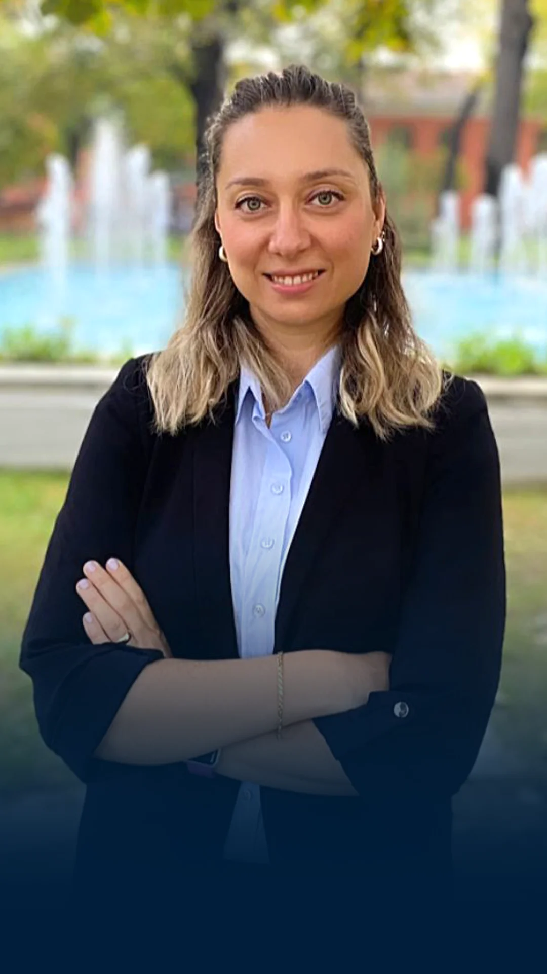 Professional woman in business attire smiling with arms crossed outdoors
