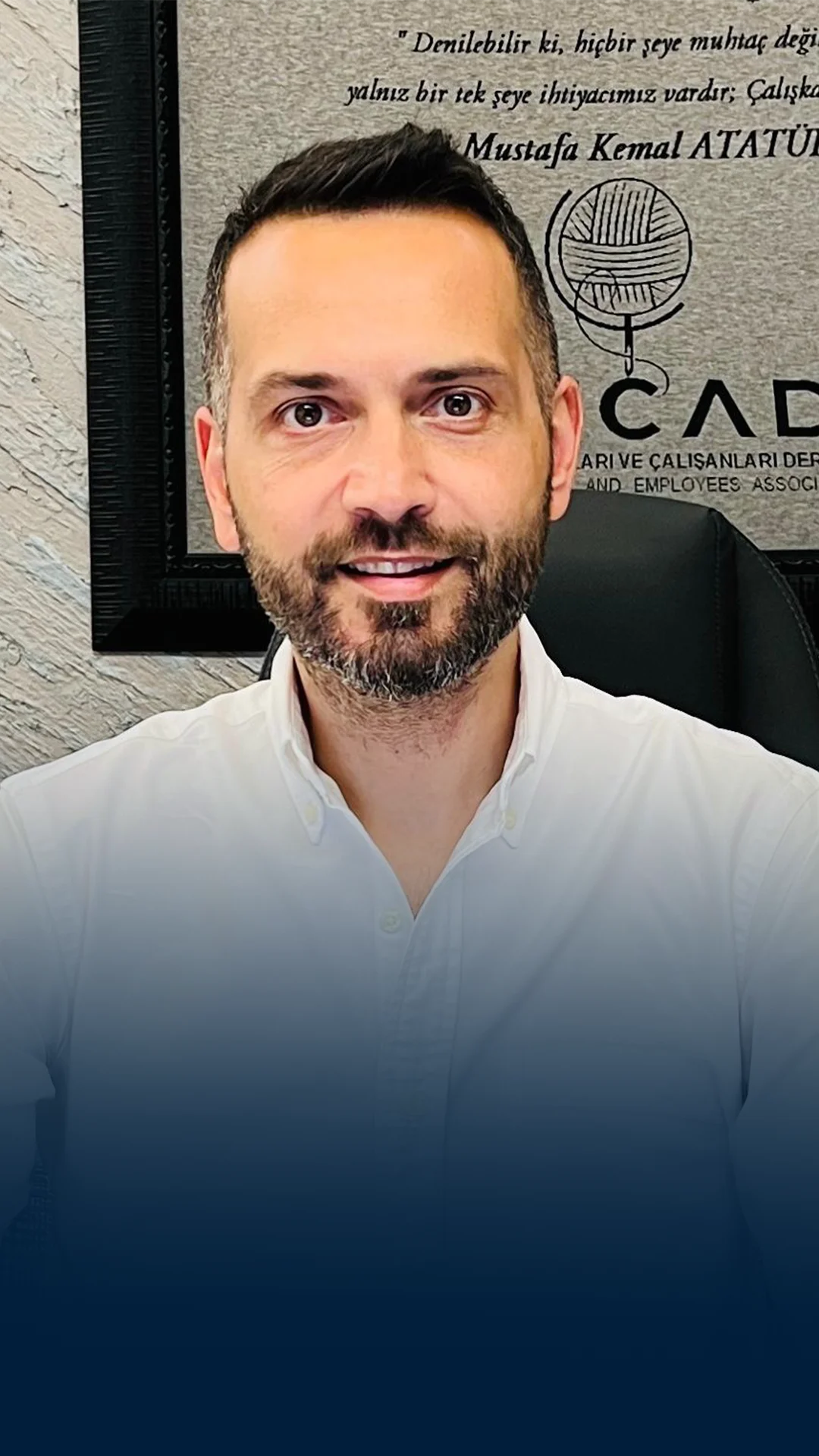 Man with beard smiling at camera wearing white shirt indoors