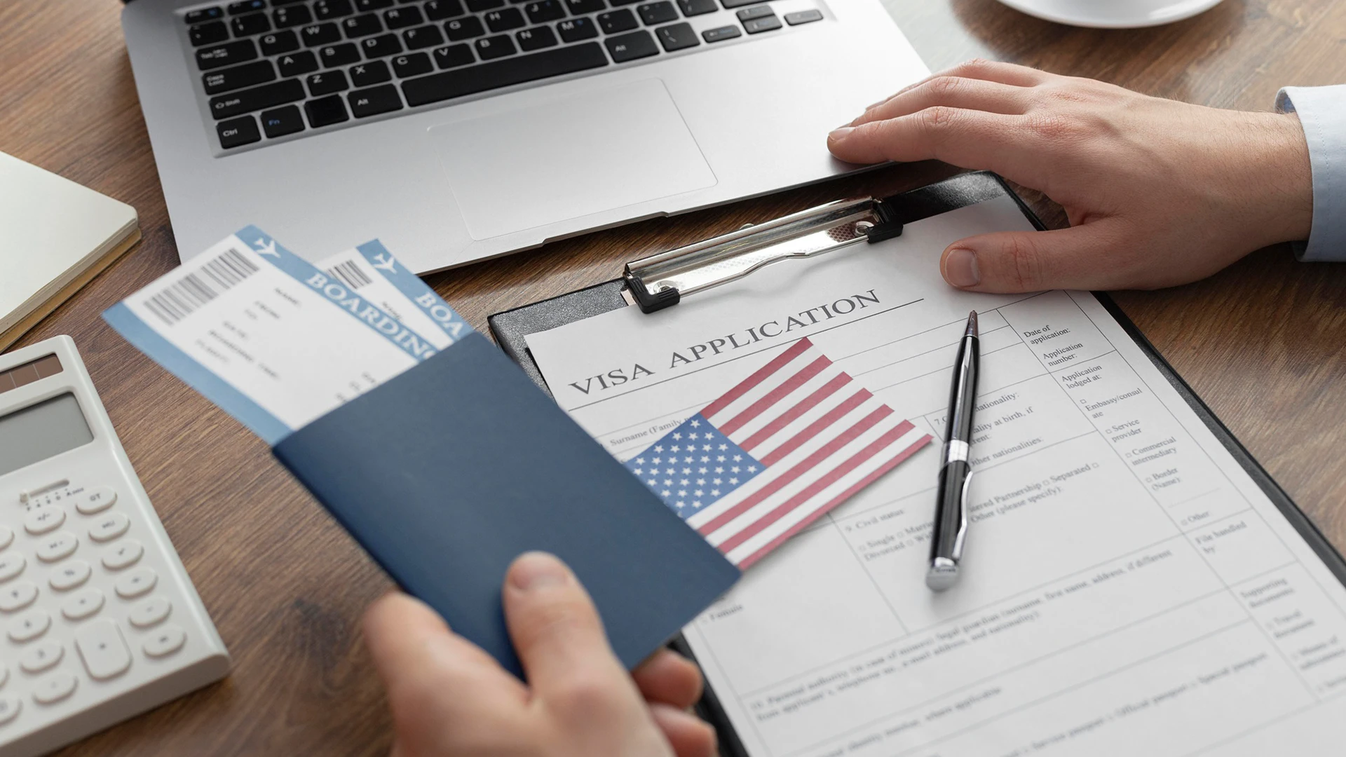 Person holding a passport and pen reviewing a U.S. visa application