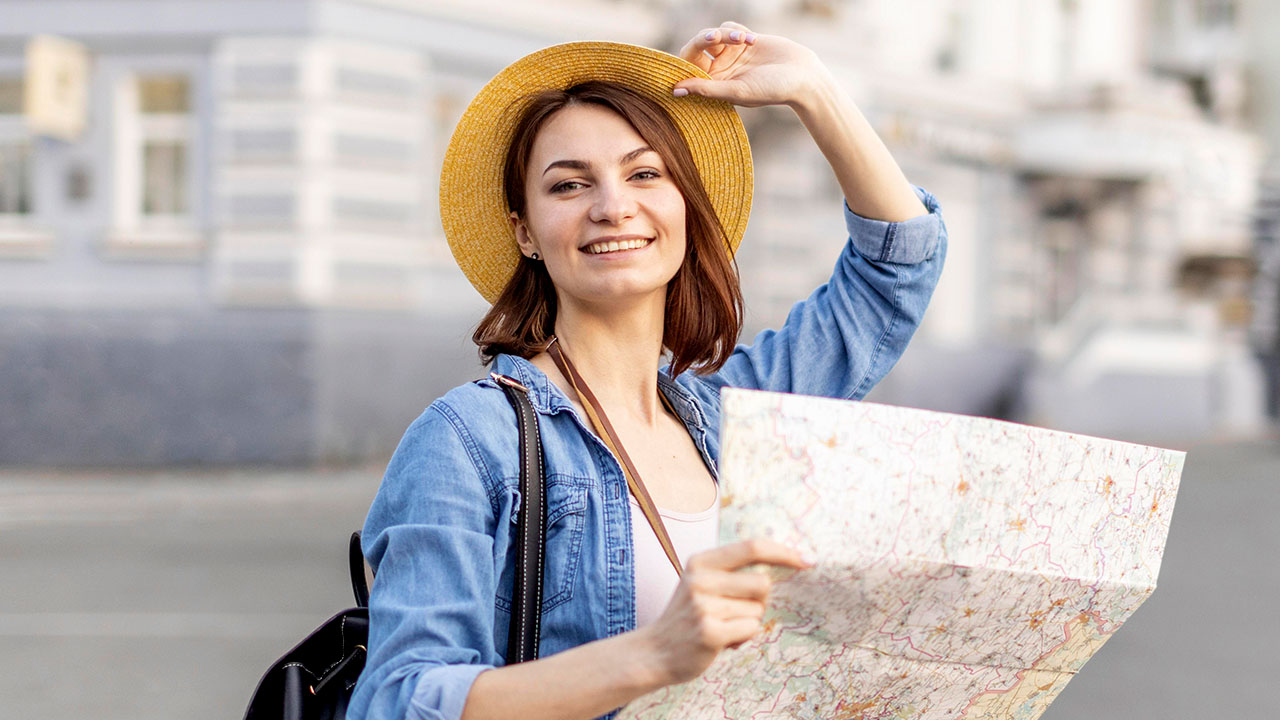 Smiling tourist in a straw hat holds a city map, expedited interview fee for B1 B2 visa applicants