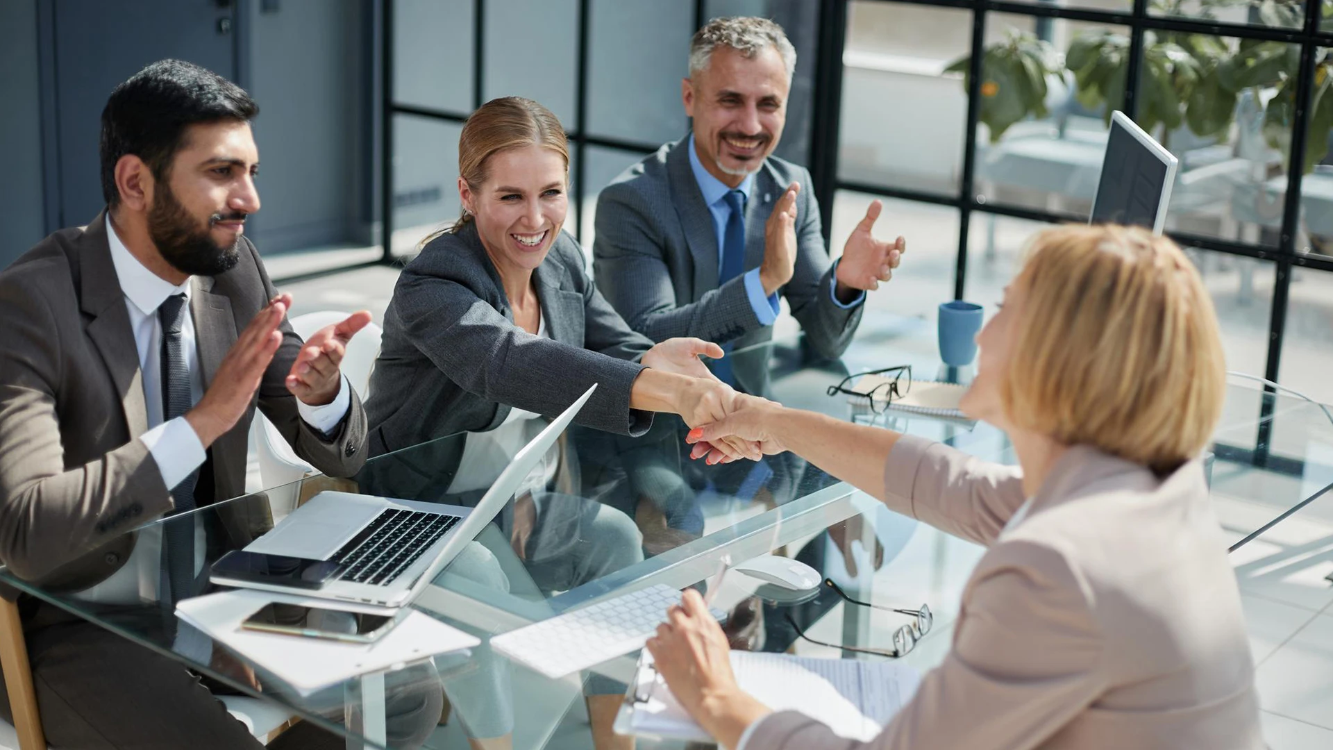 Business colleagues shake hands at an office meeting table, L-1 visa to green card process