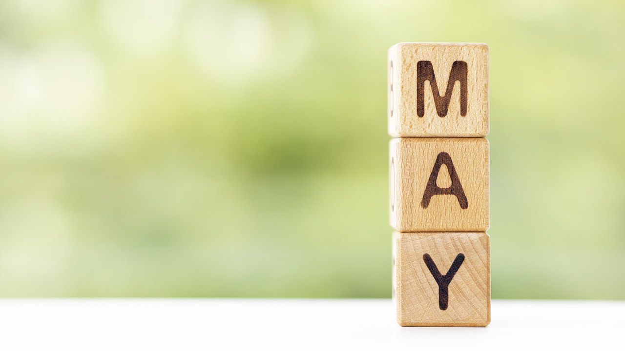 Stacked wooden blocks spell May against soft green foliage, May 2026 visa bulletin