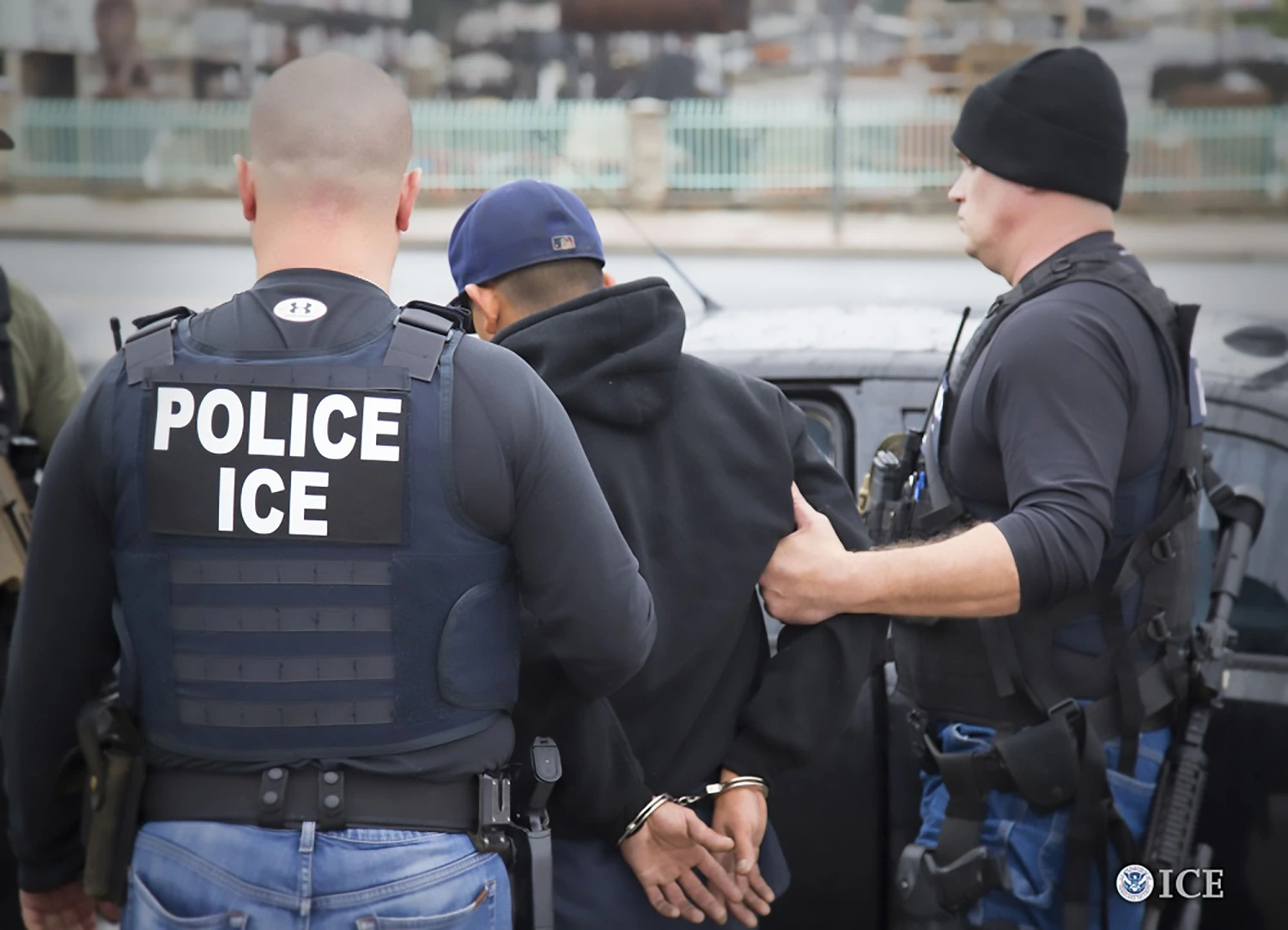 ICE officers escort a handcuffed man to a vehicle, ICE detention plan policy alert