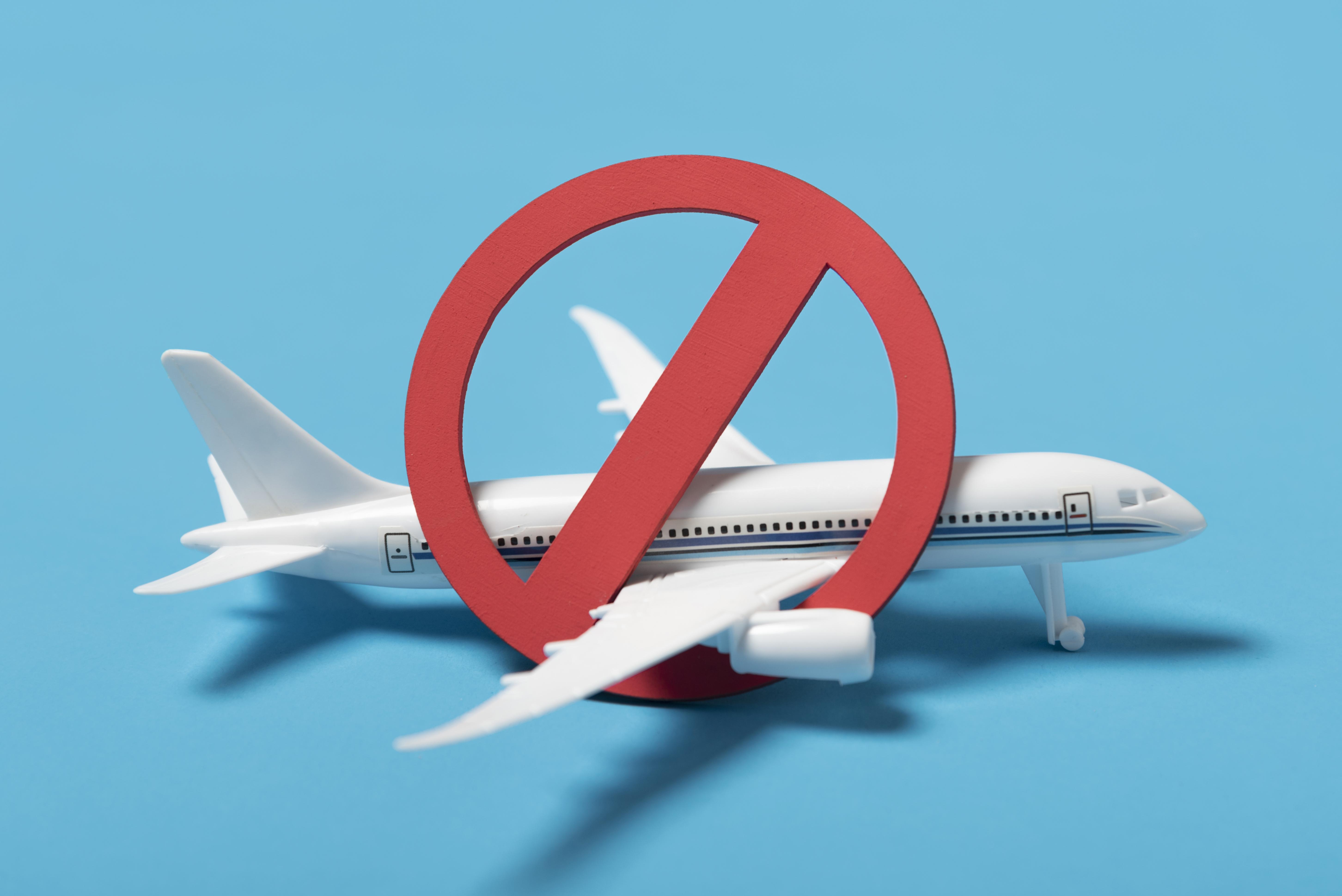 Prohibition symbol over a small plane, travel ban on 12 countries and new restrictions on 7 others