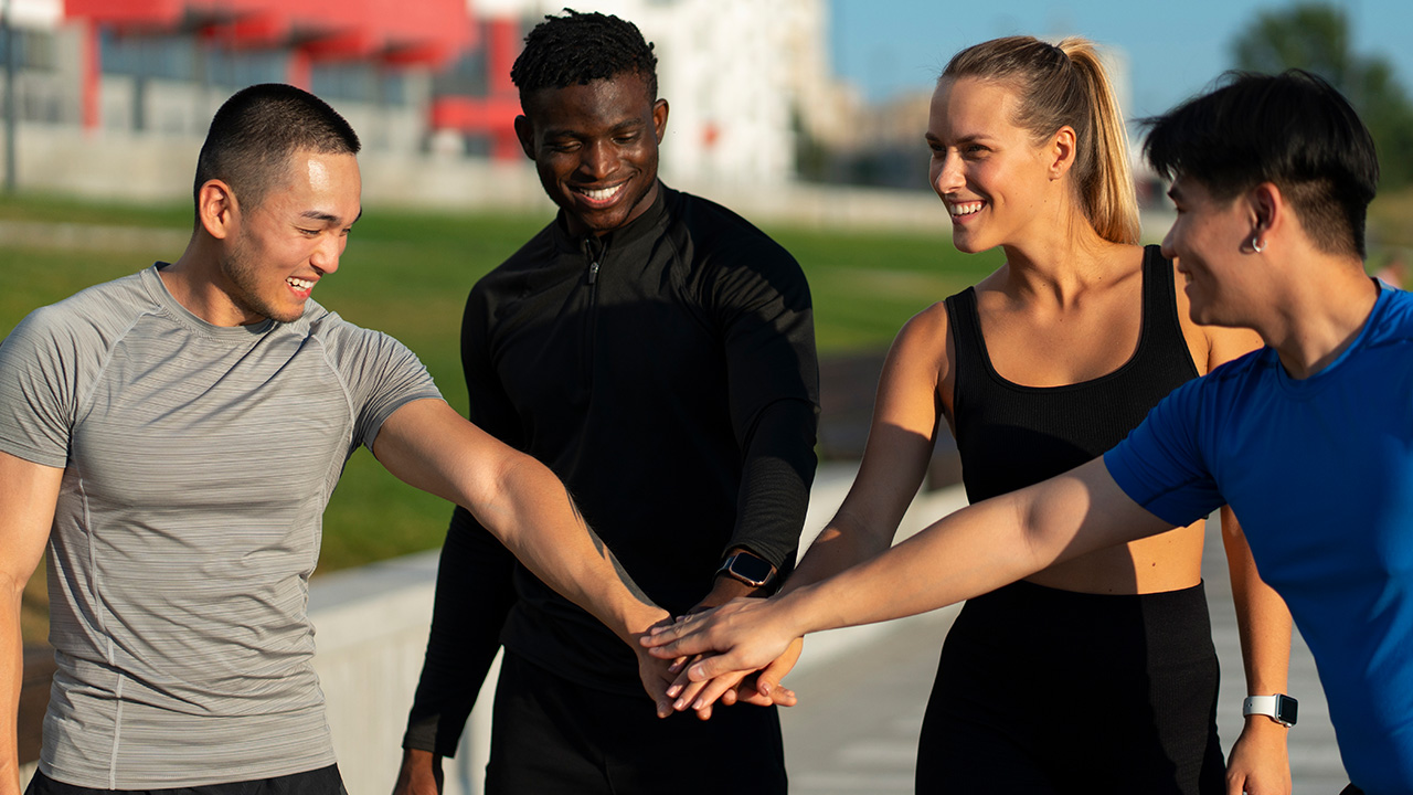 Four athletes in sportswear stack hands outdoors, immigration requirements for professional athletes