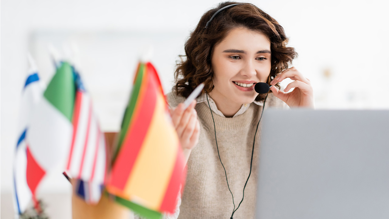 Interpreter with a headset works at a laptop near international flags, USCIS interview interpreter rules