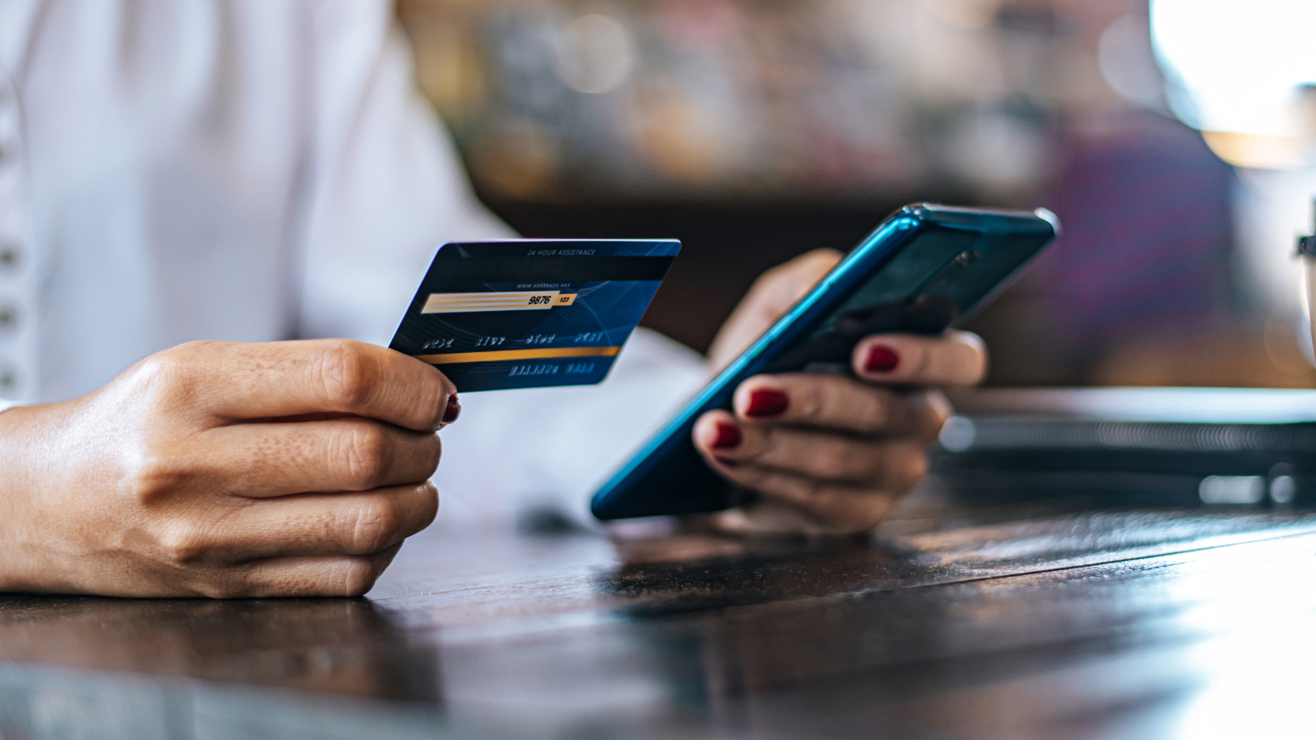 Hands holding a credit card and smartphone for online payment, USCIS transition to electronic payments