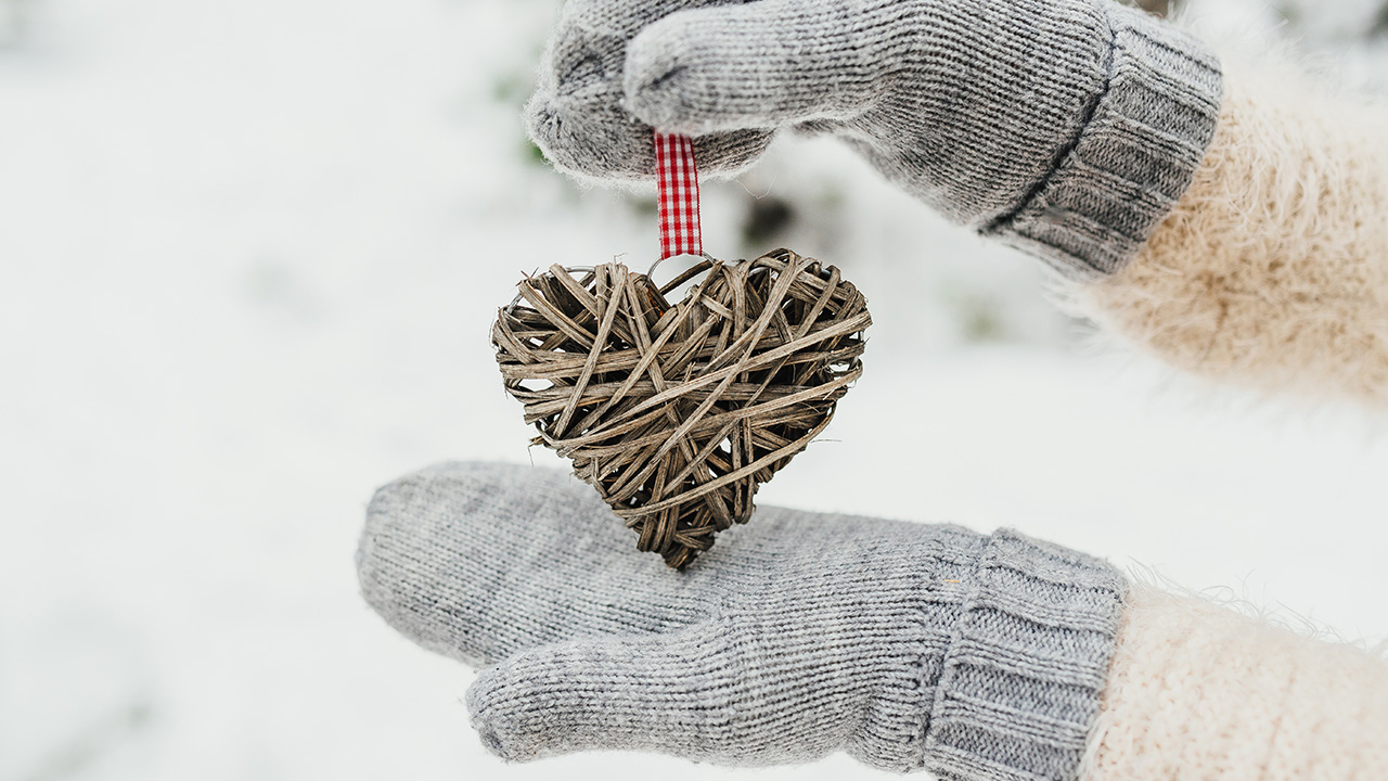 Gloved hands hold a wicker heart ornament in the snow, January 2026 visa bulletin