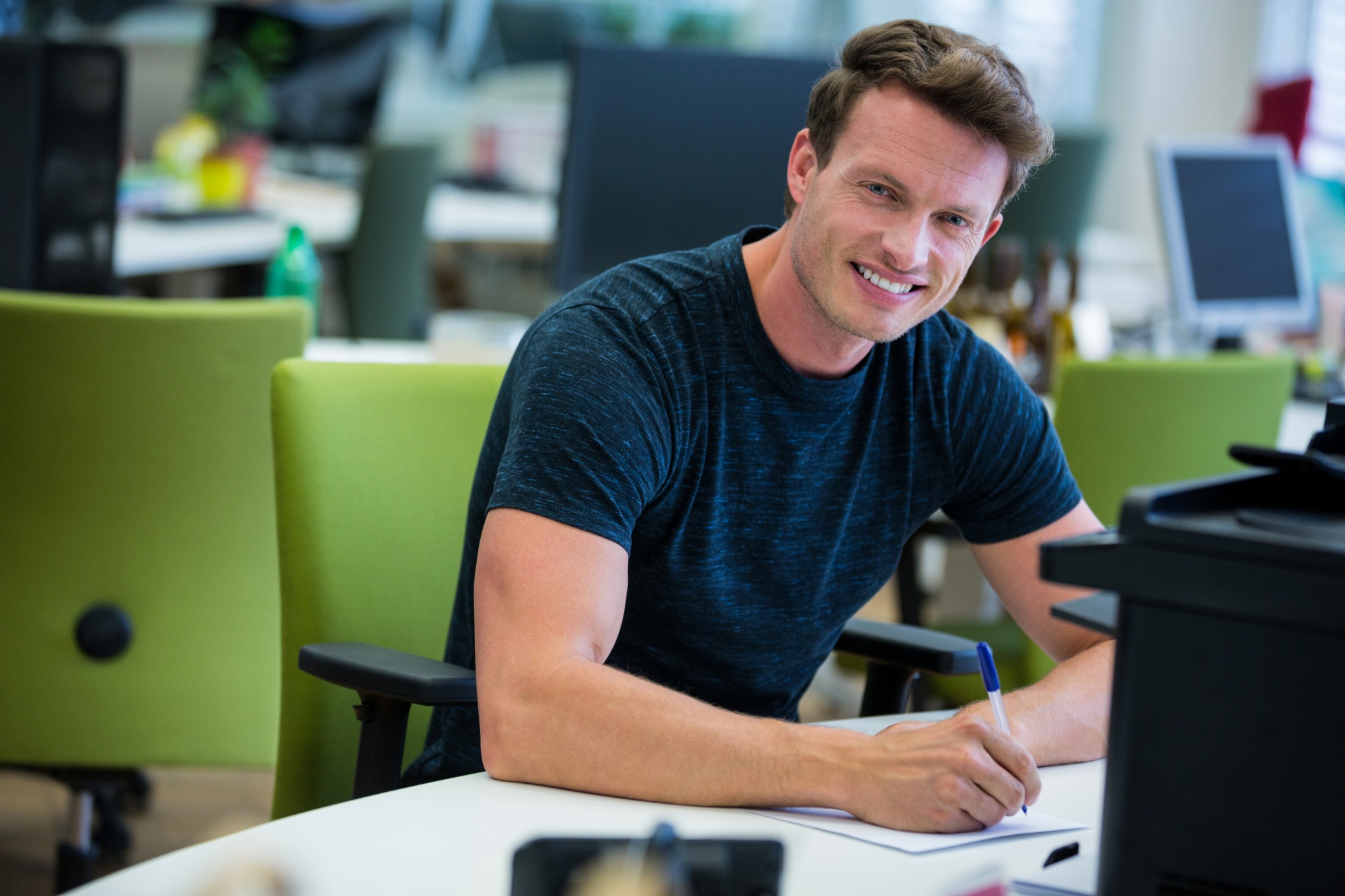 Smiling professional at a desk, EB-2 NIW for academics and researchers