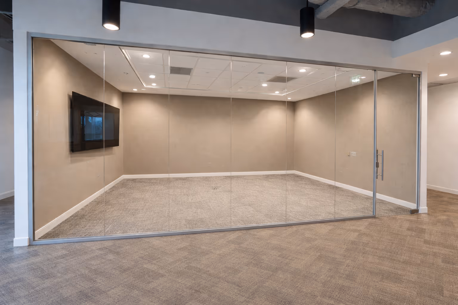 Empty modern office meeting room with glass walls and a wall-mounted TV.