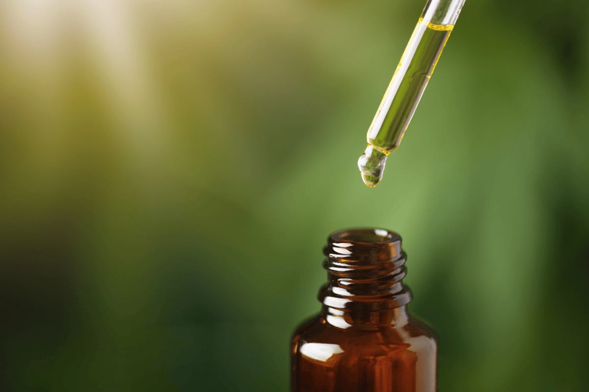 Dropper with CBD oil dropping into amber bottle