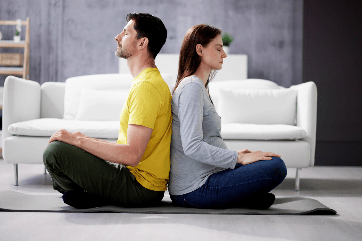 Couple back to back meditate on floor