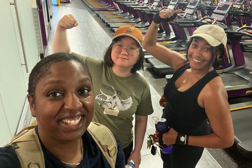 Coach Katrina taking a selfie and smiling with two women clients who are flexing their biceps.