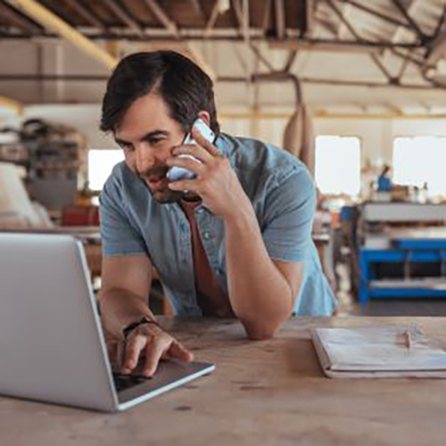 a man working on a laptop while talking on the phone