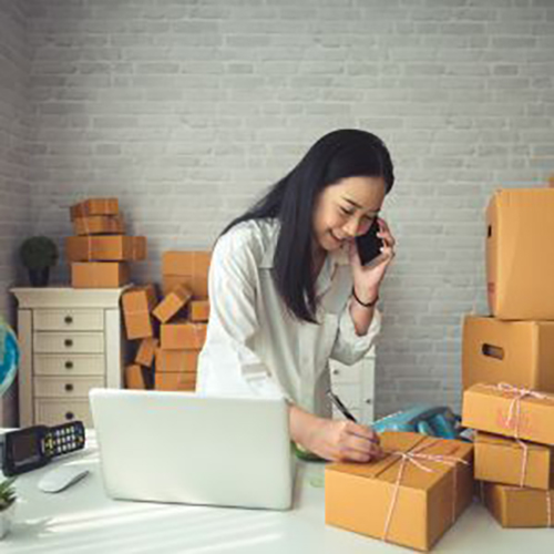 a women writing on box while talking her phone