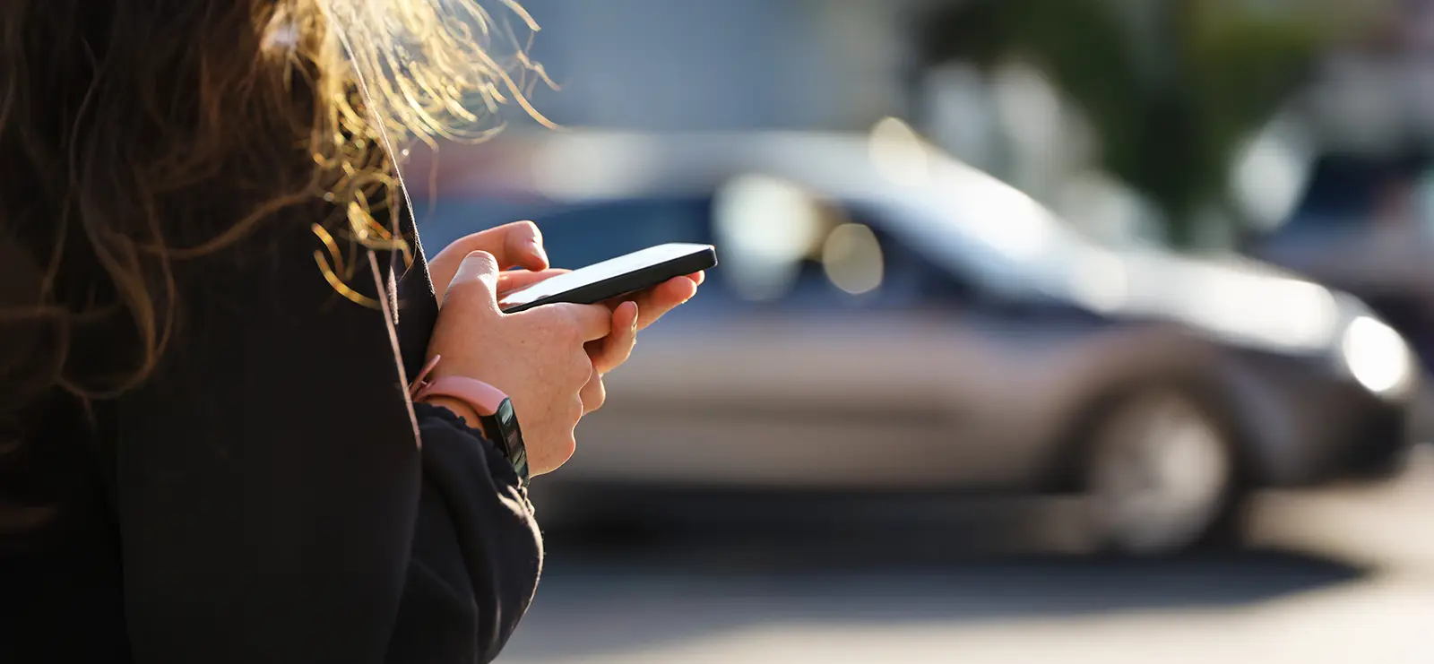 a young woman on her phone standing in front of her brand new car
