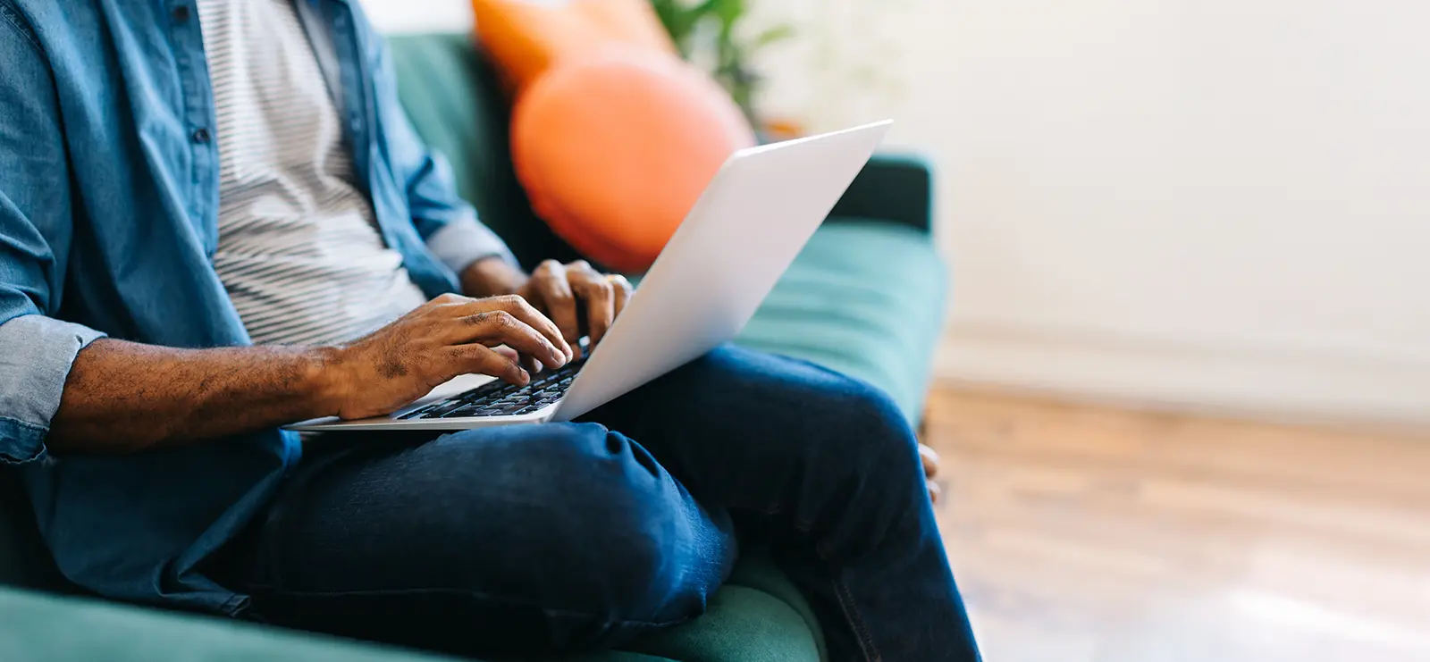a man sitting on a couch typing on a laptop