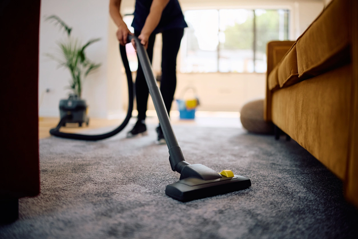 A woman vacuuming a carpet with a vacuum cleaner.