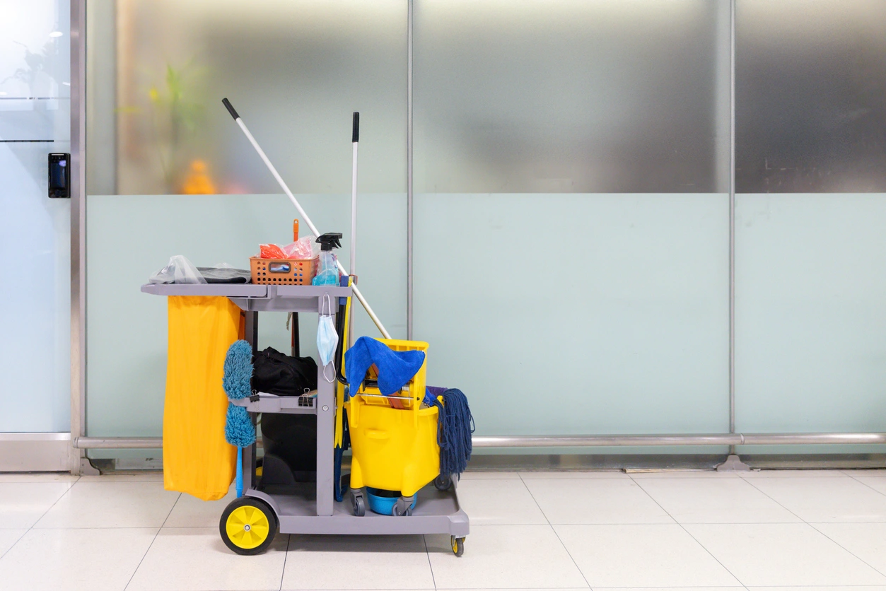 A cleaning cart filled with supplies is positioned in a hallway.