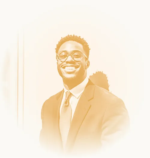 Smiling man in a suit and glasses standing confidently.