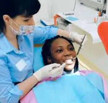 A woman getting her teeth brushed by a dentist.