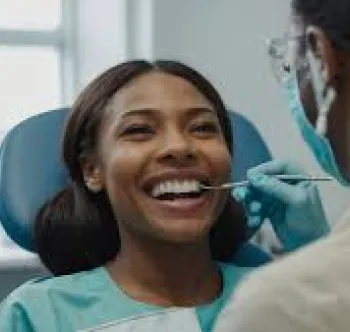 A smiling woman getting her teeth checked by a dentist.