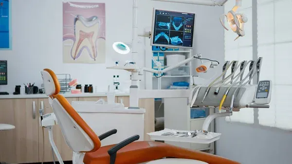 A dentist's office with a dental chair in the foreground.