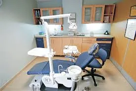 A dentist chair in a room with a light on.