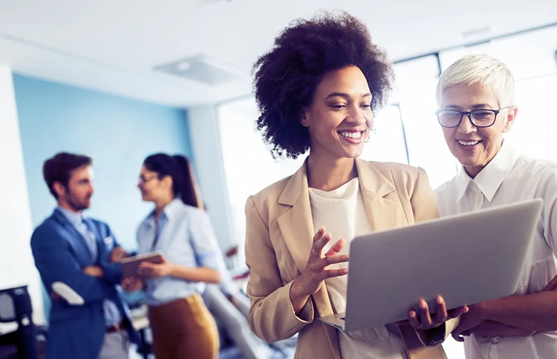 A couple of people that are looking at a laptop.