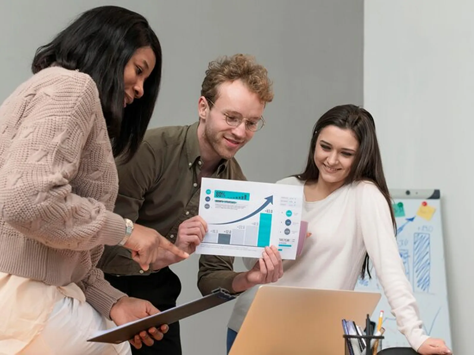 A group of people standing around a laptop computer.