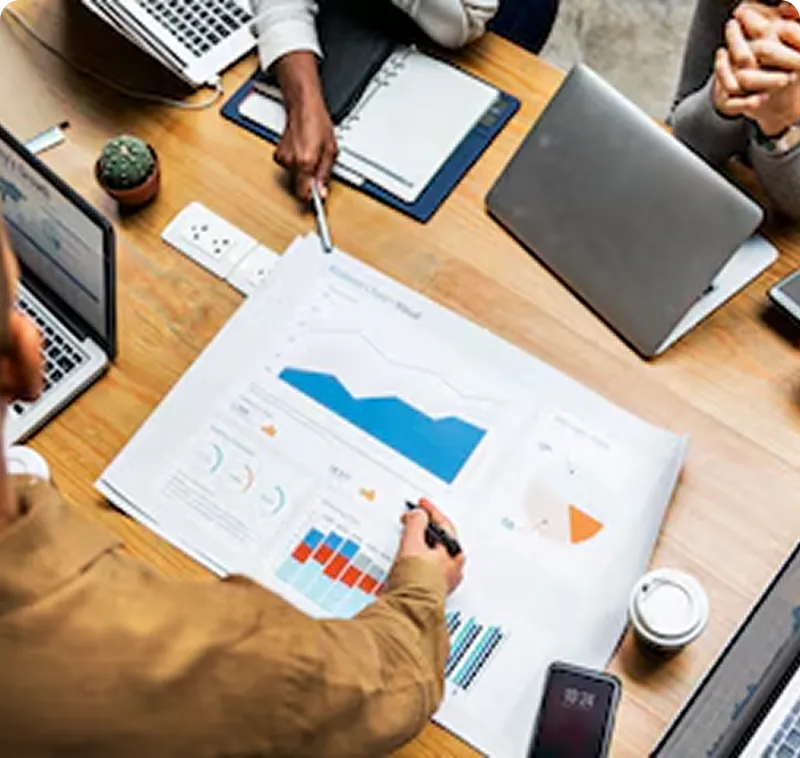 A group of people sitting around a table with laptops.