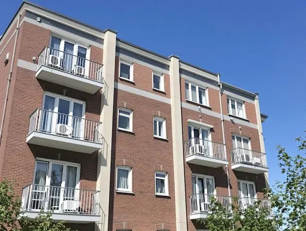 Immeuble résidentiel avec pompes à chaleur installées sur les balcon, illustrant l'installation de systèmes de chauffage et climatisation en location