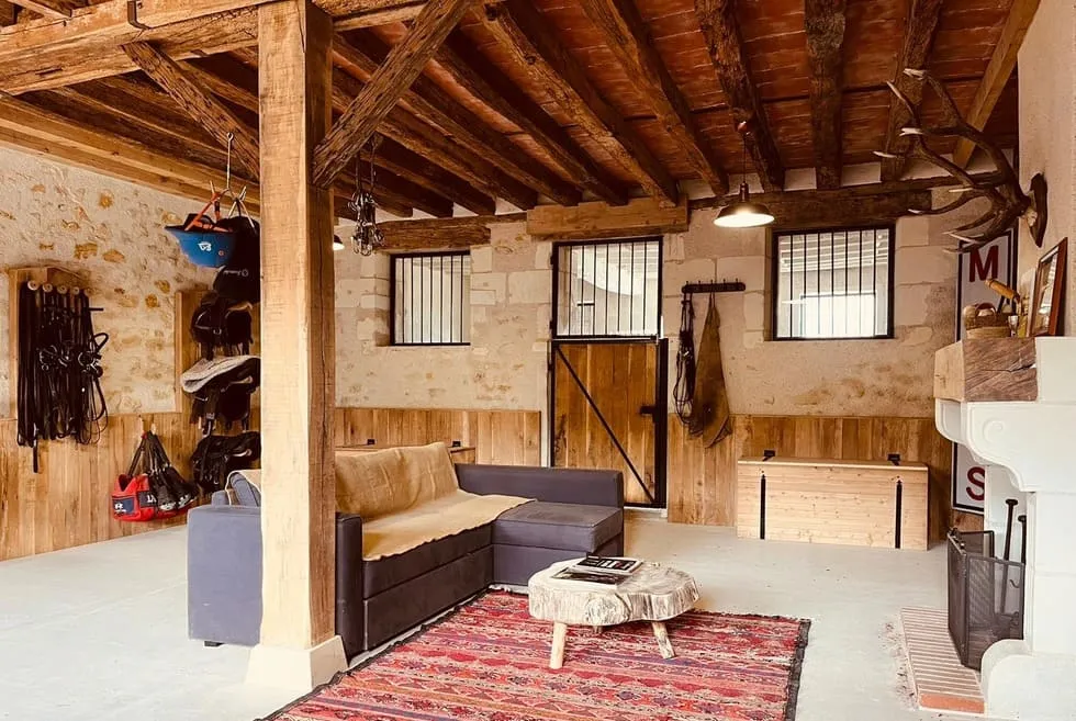 Les anciennes écuries transformées en espace lounge : canapé, feu de cheminée et bar