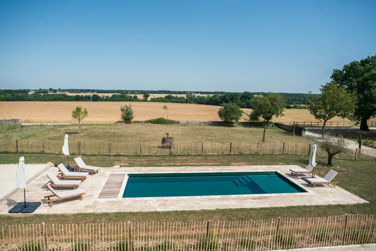 La piscine chauffée et le champ en agriculture bio en arrière plan.