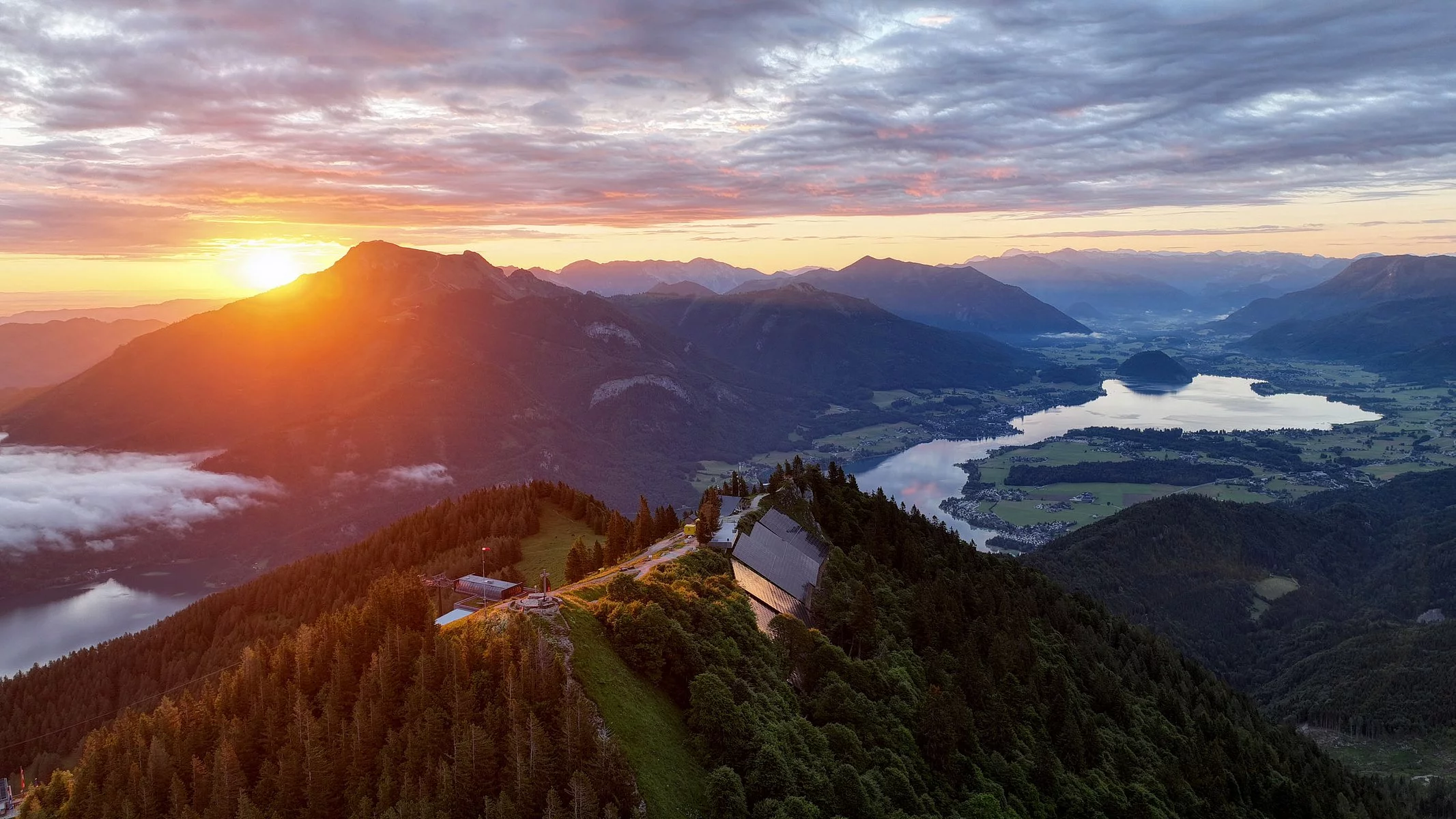 Sonnenaufgang über dem Zwölferhorn mit Blick auf Wolfgangsee und umliegende Alpenlandschaft