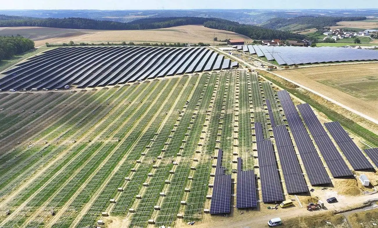 Großflächiger Solarpark mit Photovoltaik-Feldern in ländlicher Umgebung
