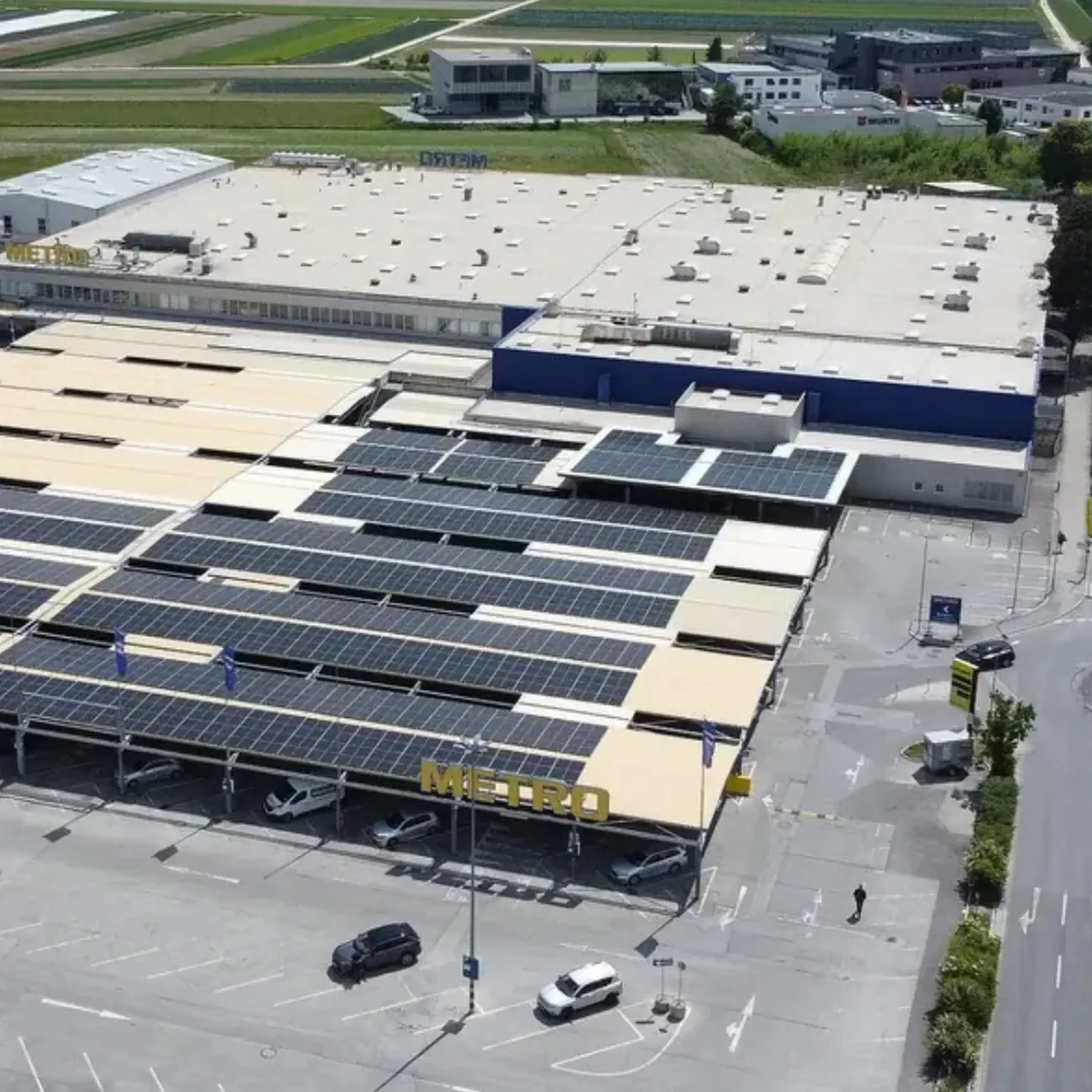Photovoltaik-Carportanlage auf dem Parkplatz des METRO-Markts in Rum, installiert von Elevion Green. Die PV-Module bedecken die gesamte Carportfläche vor dem Hauptgebäude.