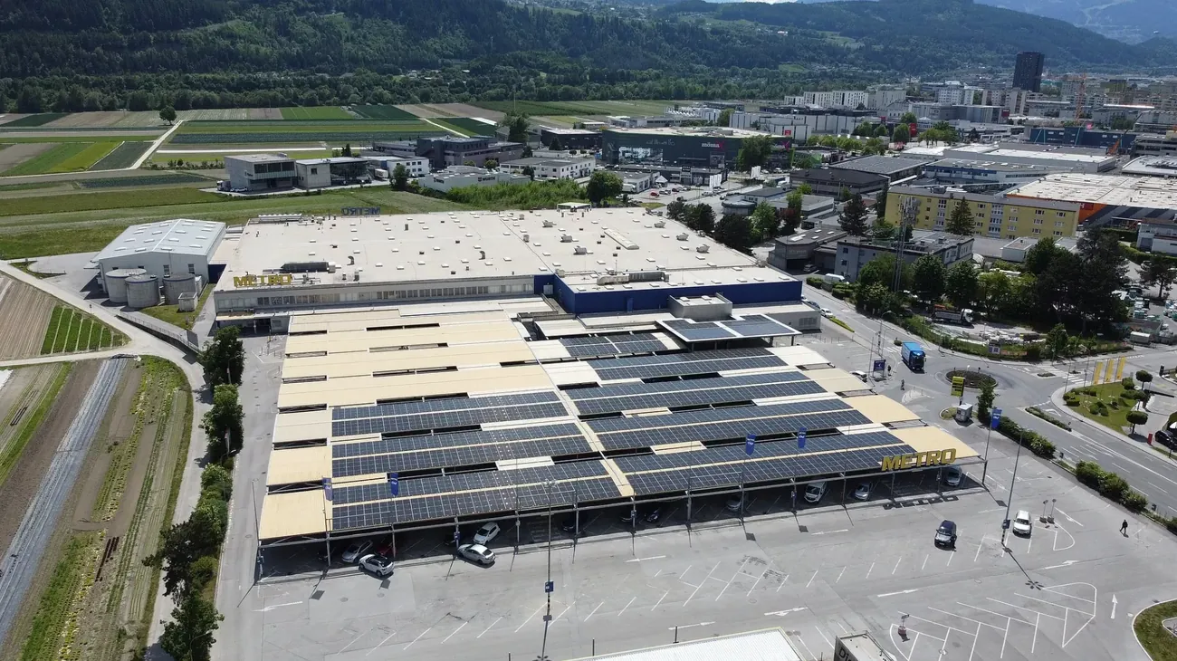 Luftaufnahme der großflächigen PV-Carportinstallation am METRO-Standort in Rum. Die Solaranlage erstreckt sich über die komplette Parkfläche, umgeben von Feldern und urbaner Infrastruktur.