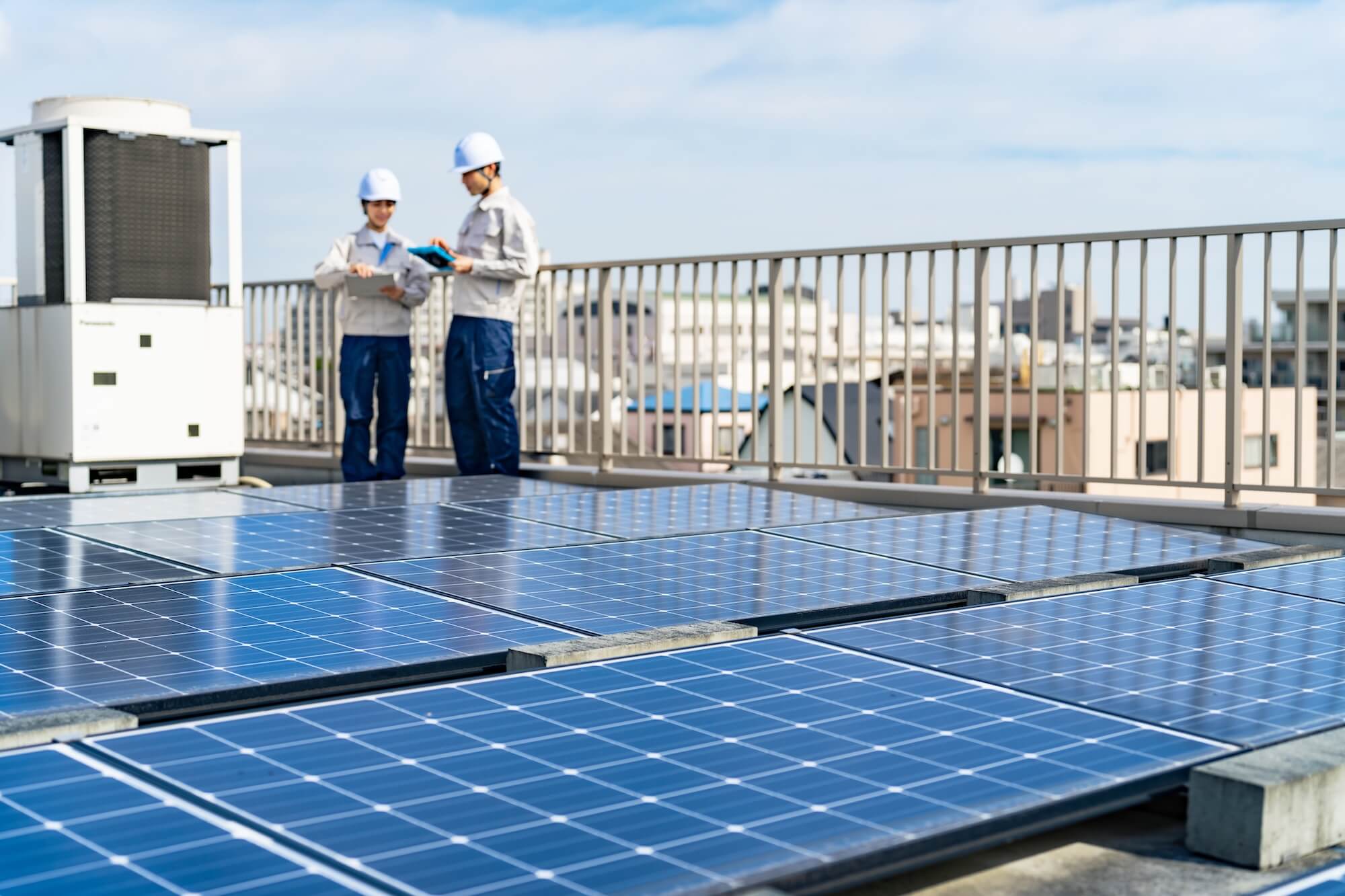 Zwei Solartechniker inspizieren Photovoltaikanlage auf einem Firmendach mit Solarpaneelen