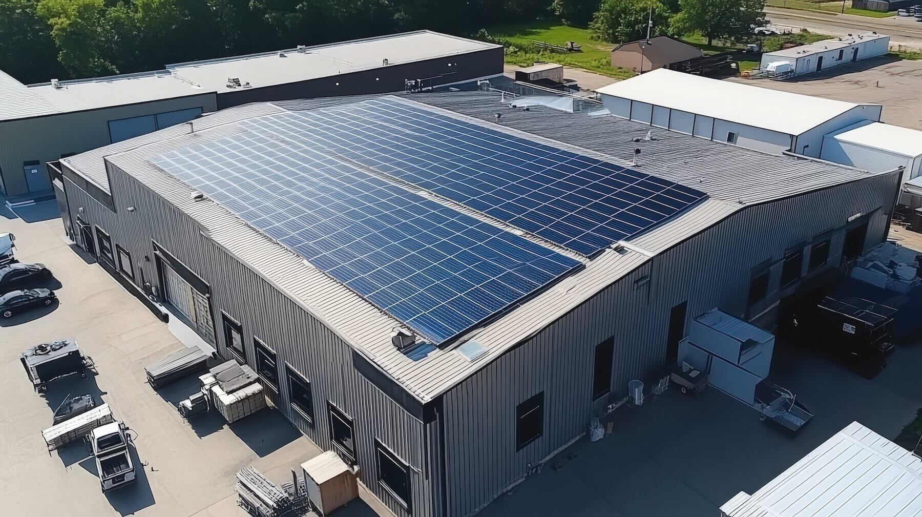Moderne Industriehalle mit großer Solaranlage auf dem Dach - Luftaufnahme eines Gewerbebetriebs