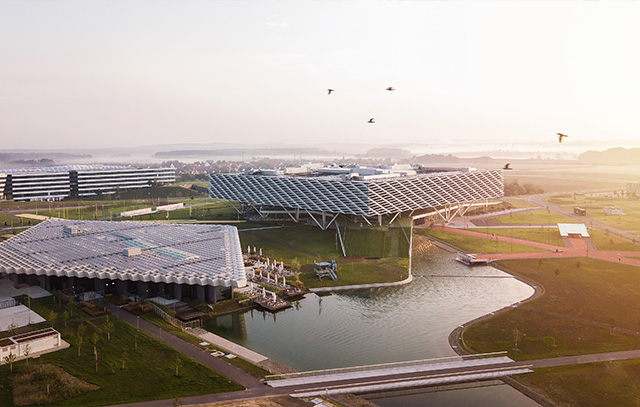 Luftaufnahme des Adidas World of Sports Campus in Herzogenaurach mit modernen Gebäuden, Wasserflächen und Solardächern im Morgenlicht.