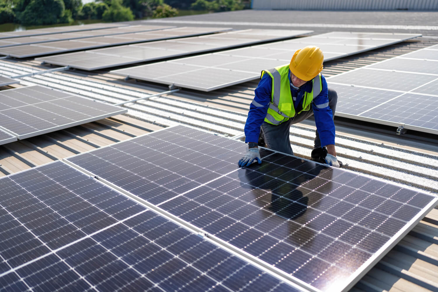 Handwerker installiert eine PV-Anlage auf dem Dach einer Gewerbehalle