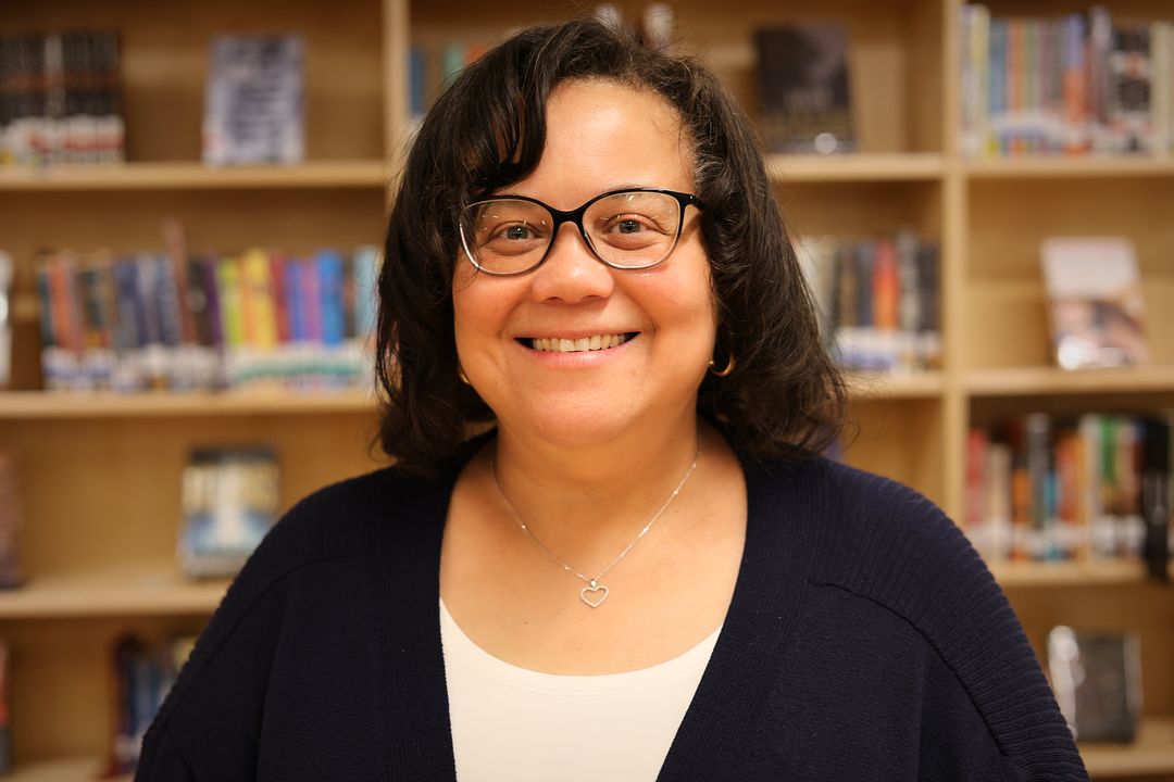 Margaret Cabanilla smiling in front of library bookshelves