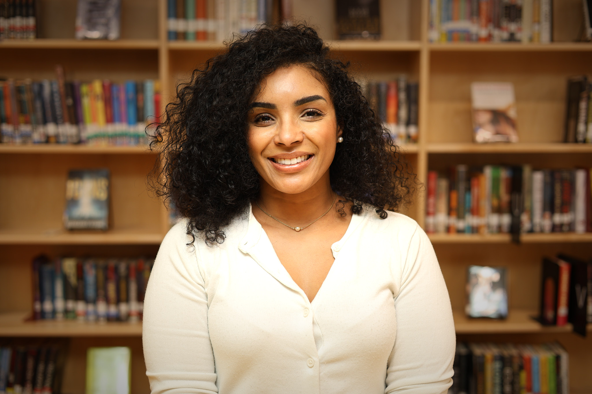 Maziel Concepcion smiling in front of school library bookshelves