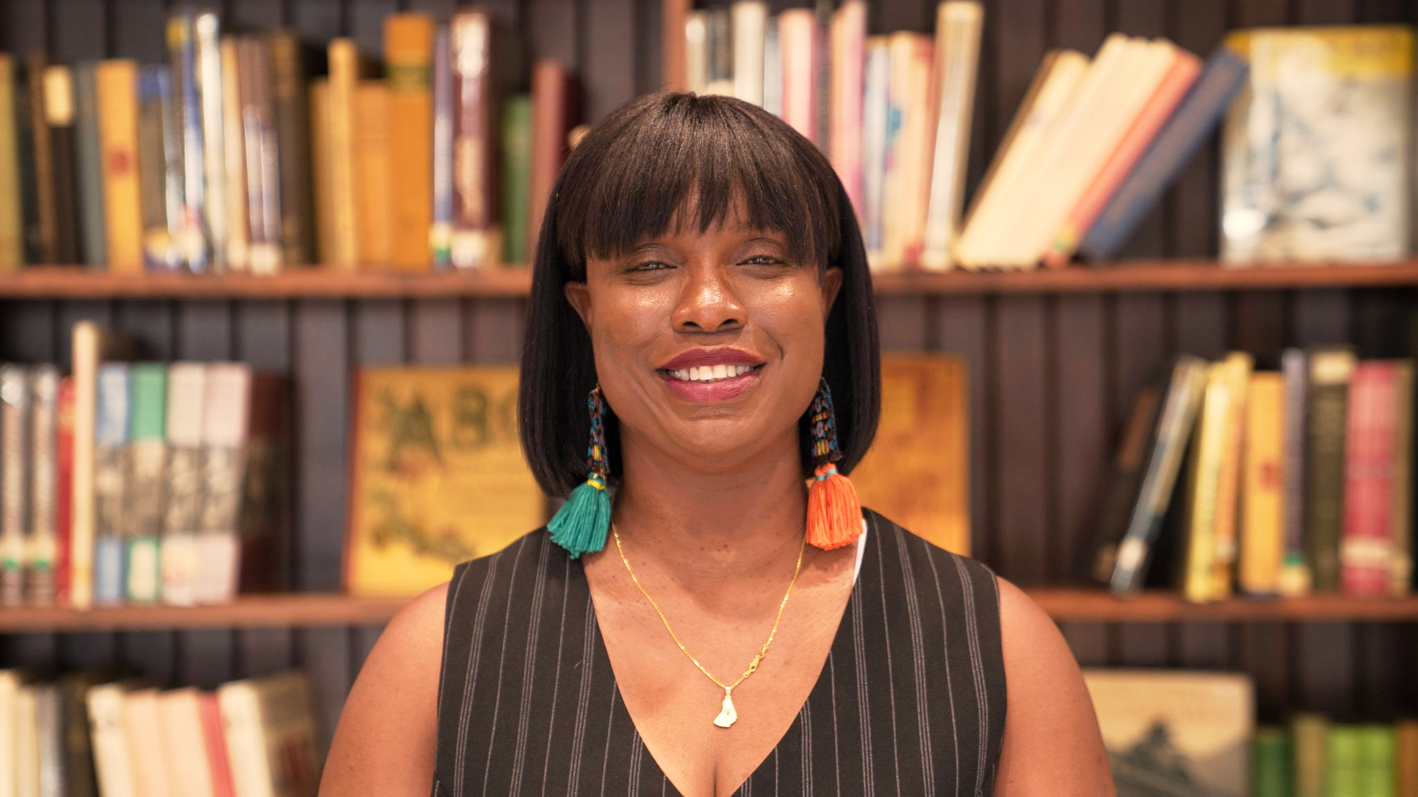 Antoinette Spencer smiling in front of a library bookshelf