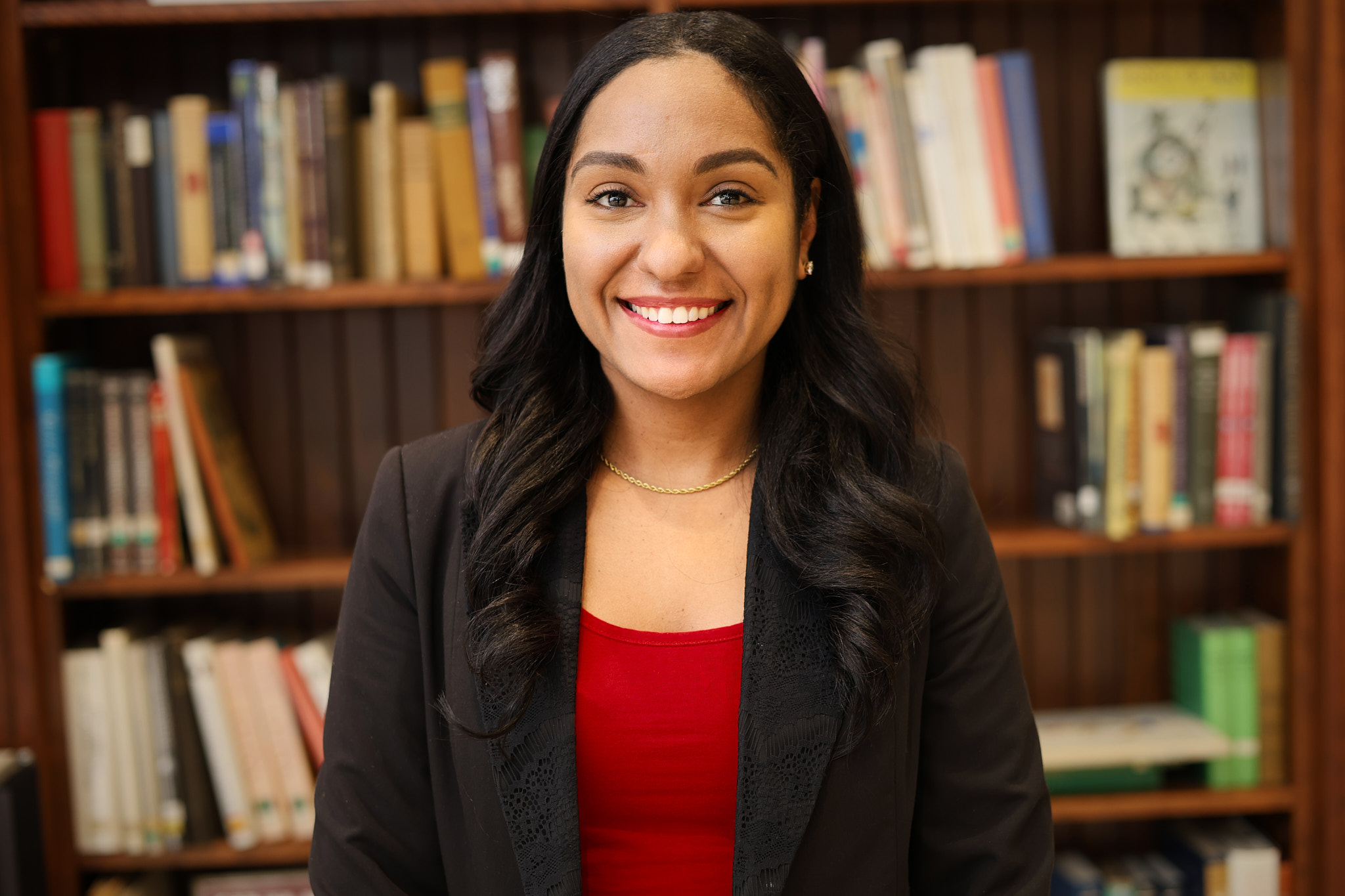 Denise DelRosario smiling in front of a bookshelf
