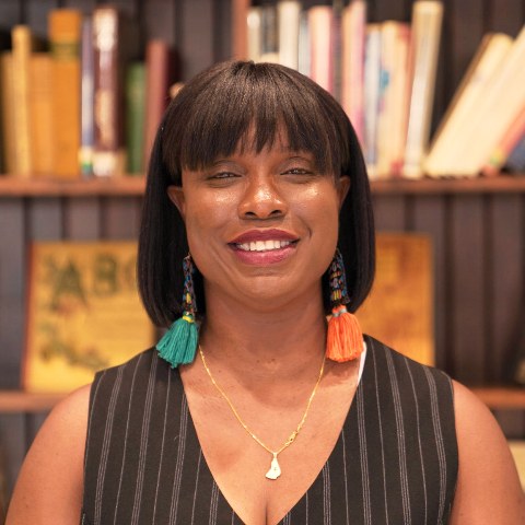 Antoinette Spencer smiling in front of a library bookshelf