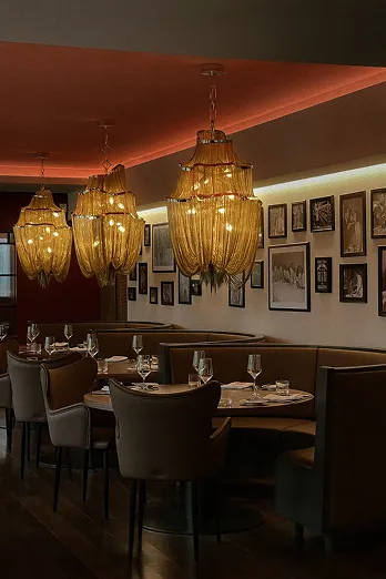 Stilvoll eingerichteter Restaurantbereich mit warmen Licht, Kronleuchtern und Bildern an der Wand.